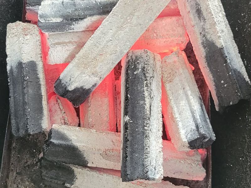 Sawdust briquettes burnt down to embers, still holding their bar shape